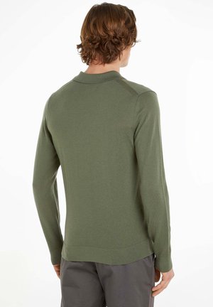 Olivgrüner Strickpullover mit langen Ärmeln, leichtem Stehkragen und figurbetontem Schnitt. Glatte Textur mit gerippten Akzenten an Bündchen und Saum.