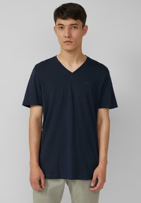 Granatowa koszulka polo z krótkim rękawem, wykonana z miękkiego materiału, z subtelnym detalem logo na piersi i luźnym krojem.