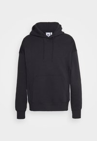 Černá mikina s kapucí vyrobená z měkké tkaniny, s přední kapsou, stahovací kapucí a nenápadným logem na hrudi. Dlouhé rukávy s žebrovanými manžetami.