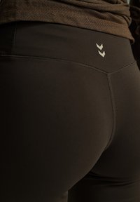 Obcisłe, czarne legginsy o gładkiej, matowej fakturze. Posiadają małe logo oraz kontrastowe przeszycia wzdłuż talii i szwów.