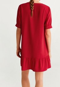 Czerwona sukienka z krótkim rękawem i rozkloszowanym dołem, wykonana z lekkiego materiału. Posiada podwinięte rękawy i luźny krój. Gładka tekstura.