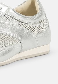 Sølv lærersneaker med nettingpaneler, lavprofil-design, glatt tekstur og lysfarget gummisåle.