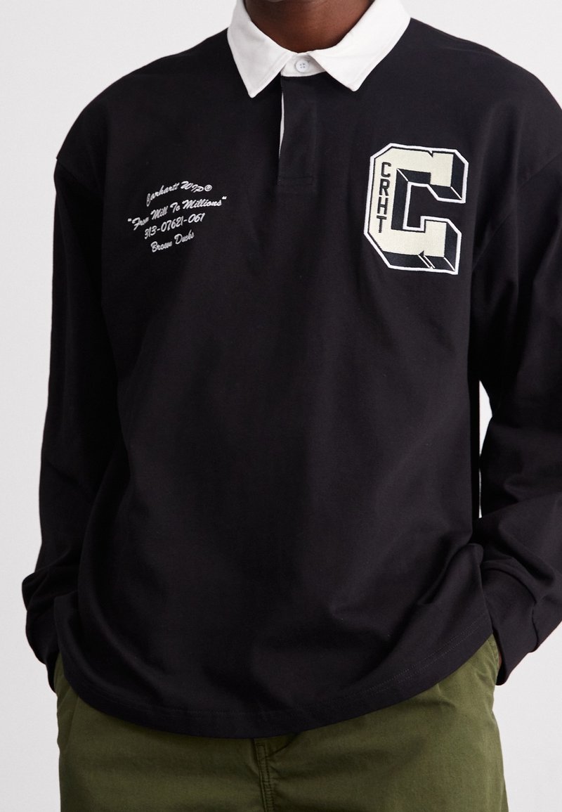 Schwarzes Polohemd mit langen Ärmeln und weißem Kragen; verfügt über gestickte Schriftzüge und ein kontrastierendes "C"-Logo auf der Brust. Baumwollmaterial.