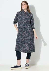 Námořnické šaty s růžovým vzorem listů, dlouhými rukávy a stahovaným výstřihem. Spárovány s tmavými legínami s vlnkovanými lemy a teniskami.