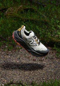 Lichtgewicht hardloopschoen in off-white met zwarte en oranje accenten, voorzien van een gemêleerd mesh-bovenwerk en een agressieve zool voor grip.