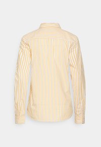 Chemise à manches longues vue de dos, avec des rayures verticales jaunes et blanches, poignets boutonnés et col classique. Matière en coton.