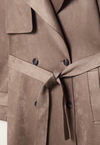 Taupe suede trench coat with a tied belt, dark buttons, wide lapels, and stitched rectangular pockets.