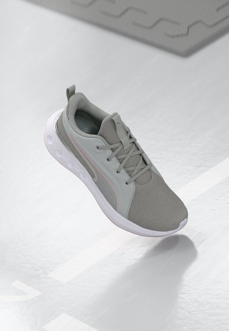 Light gray athletic shoe with a mesh upper, lace closure, white sole, and a pink accent along the side. Features a padded collar and tongue.