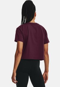 Kort t-shirt i djup bordeauxfärgad bomull med rund halsringning och korta ärmar, kombinerad med svarta tajta leggings.