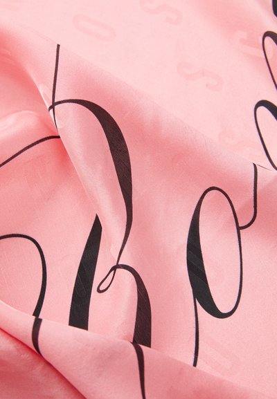 Rosa Textil mit fett gedruckter schwarzer Kursivschrift, glatter Textur und subtil gemustertem Hintergrund, der visuellen Kontrast und Tiefe schafft.