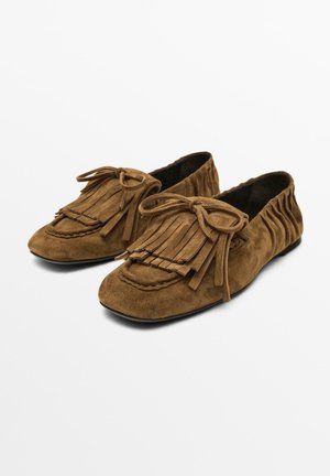 Brązowe zamszowe buty w stylu mokasynów z frędzlami i akcentami w postaci kokardy, o miękkiej fakturze i elastycznej konstrukcji.