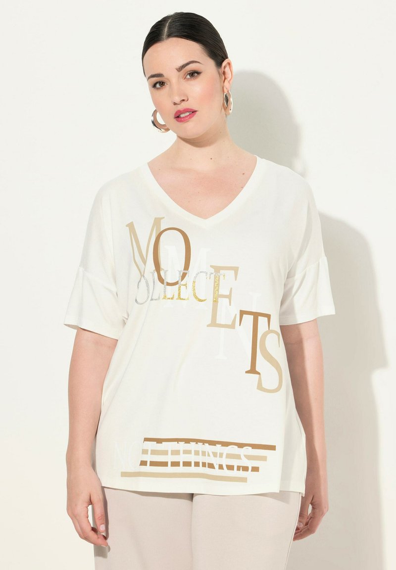 Hvid V-hals T-shirt med korte ærmer, med guld- og metalgrafik, der viser teksten "MOMENTS" og "NOTHINGS" i forskellige stilarter.