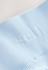 Lyseblåt ribstrikket stof med prægede bogstaver. Teksturen er blød og elastisk med jævnt spaced vertikale linjer over hele stoffet.