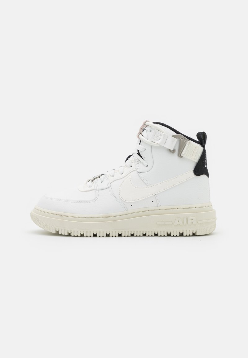 Sneakers bianche alte in pelle texturizzata, con accenti neri e una suola spessa. Presentano un evidente marchio "AIR" sul lato.