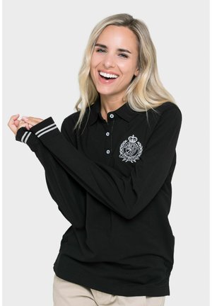 Polo de manga larga negro con un escudo bordado, que presenta un cierre de botones y puños a rayas. Fabricado en tejido suave con un ajuste relajado.