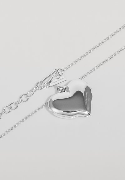 Collana con pendente a forma di cuore in argento, con una finitura lucida, bordi testurizzati, un piccolo diamante come accentuazione e una catena collegata con chiusura.