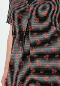 Tessuto a righe bianche e nere con motivo floreale rosso, caratterizzato da un collo a V e maniche corte. Texture liscia, design casual, parte anteriore con pieghe.