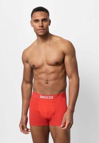 Boxer shorts rossi in cotone con il logo bianco "SNOCKS" sulla cintura, design aderente e texture liscia. Il modello è mostrato senza maglietta.