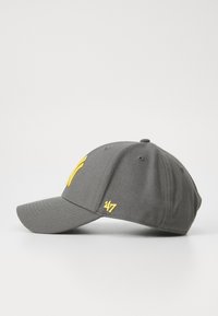 Grå baseballkasket med en struktureret krone, der har gule broderede accenter, herunder et design på fronten og et logo på siden.