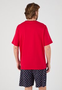 Rode korte mouwen T-shirt met een ronde hals, gecombineerd met marineblauwe shorts met een wit ankerpatroon. Casual pasvorm, zachte textuur.