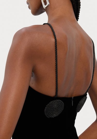 Rochie din catifea neagră cu bretele subțiri împletite și accente hardware în formă de spirală pe spate. Textură netedă cu o siluetă ajustată.