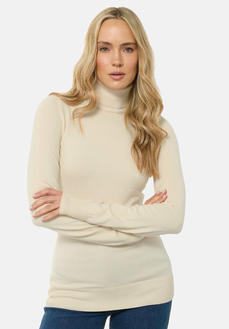Beige Rollkragenpullover aus weichem Stoff, mit langen Ärmeln und figurbetonter Passform, sowie einem gerippten Saum und Bündchen.