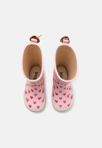 Bottes de pluie en caoutchouc rose avec un motif en cœurs dans des nuances de rose variées, accentuées par une couleur beige au talon et une doublure intérieure lisse.