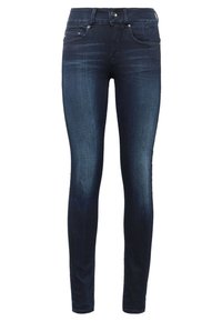 Jeans ajustados de lavado oscuro hechos de denim, con un diseño clásico de cinco bolsillos, un ligero desgastado y compartimentos de hardware metálico.