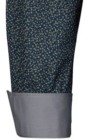 Camicia blu navy con piccolo motivo floreale bianco, con una manica grigia. Tessuto liscio con un design strutturato e su misura.