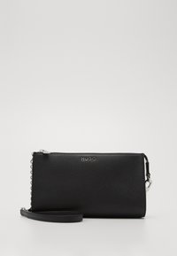 Pochette en cuir noir avec finition texturée, quincaillerie en argent et une sangle amovible pour le poignet. Comprend une fermeture zippée et le logo de la marque sur le devant.