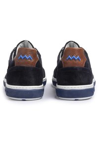 Mörkblå mockaskor med en brun läder hälla, som har blå zigzag-detaljer och en vit gummisula med texturerat grepp.
