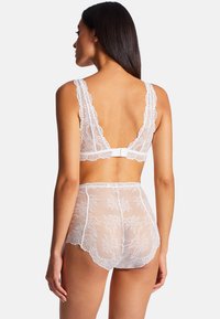 Ensemble de lingerie en dentelle blanche comprenant un bralette avec des bords festonnés et une fermeture à crochets, associé à un short taille haute en tulle.