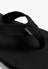 Infradito nere con una fascia in tessuto strutturato e suola in gomma solida, con un'etichetta con logo sul lato della fascia.