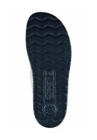 Black rubber shoe sole with wavy tread pattern, featuring a circular logo near the center and textured details along the edges.