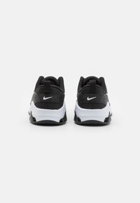 Black and white Nike sneakers with padded collar, textured black upper, white midsole, and black rubber outsole; features branding on heels.
