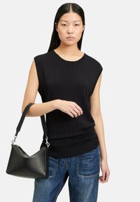 Czarna prążkowana bezrękawnikowa bluzka z okrągłym dekoltem, zestawiona z luźnymi niebieskimi dżinsami oraz czarną torebką o zaokrąglonym kształcie.