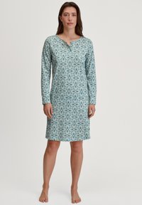 Pigiamone lungo azzurro con maniche lunghe e motivo floreale in bianco e blu scuro. Presenta un colletto henley e arriva a metà coscia.