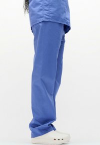 Blauwe stoffen broek met een losse pasvorm, voorzien van een recht pijpdesign en een lichte glans. Witte klompen met ventilatieopeningen maken de look af.