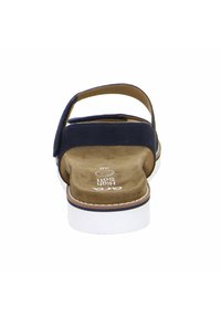 Navy blue sandals with a suede upper, adjustable back strap, and cushioned tan insole. Features a white rubber sole with a decorative border.