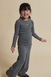 Sivá košeľa s dlhými rukávmi a nohavice s rovným strihom a zdobené volánikmi. Košeľa má malý detail srdca na hrudi. Pohodlná, mäkká textúra.