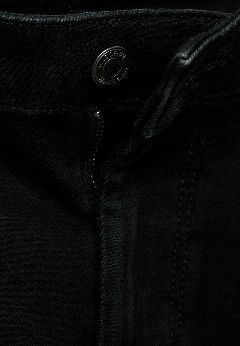 Tissu en denim noir avec une braguette zippée visible et un bouton en métal. La vue rapprochée montre une texture lisse et des détails de couture subtils.