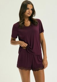 Burgundy pajama set featuring a short-sleeve top with lace trim and matching shorts with lace accents at the hem, soft fabric, relaxed fit.