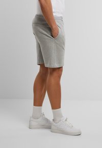 Grijze katoenen shorts met een elastische tailleband, zijzakken en een relaxed fit, gecombineerd met witte sportsneakers en crew-sokken.