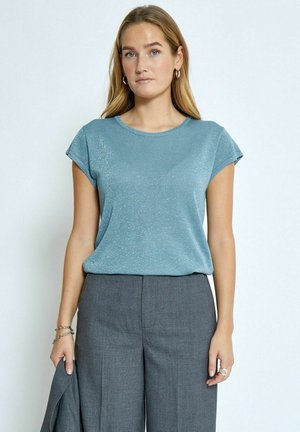 Maglietta azzurra chiara a maniche corte con un leggero effetto lucido, scollo rotondo e vestibilità rilassata, abbinata a pantaloni grigi sartoriali.