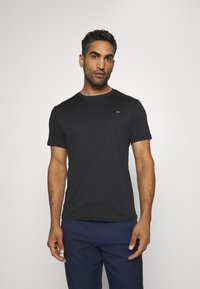 Zwart kortemouwen t-shirt met een ronde halslijn en een subtiele CK-logo op de borst; gemaakt van gladde, lichte stof.