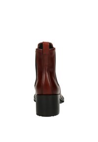 Bottine en cuir marron avec une texture lisse, des panneaux élastiques sur les côtés et un talon épais noir, dotée d'une languette à l'arrière pour un enfilage facile.