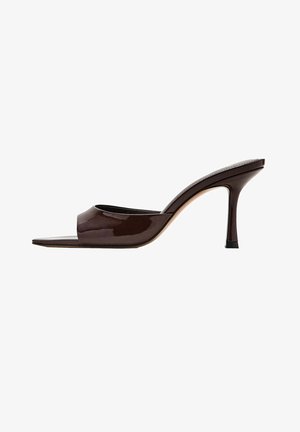 Zueco de charol marrón oscuro con puntera abierta, correa ancha y tacón alto y delgado sobre fondo blanco.