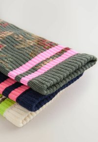 Strikkede sokker i grøn, marineblå, pink og creme, med teksturerede mønstre og kontrasterende striber i pink og marineblå, lavet af blødt uldmateriale.