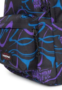 Mochila de tela negra con patrones abstractos en azul y púrpura. Presenta un bolsillo frontal con cremallera y etiqueta con el logo de Eastpak.