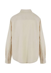 Chemise beige à manches longues avec poignets boutonnés, vue de dos unie, col structuré et couture simple sur le haut du dos.